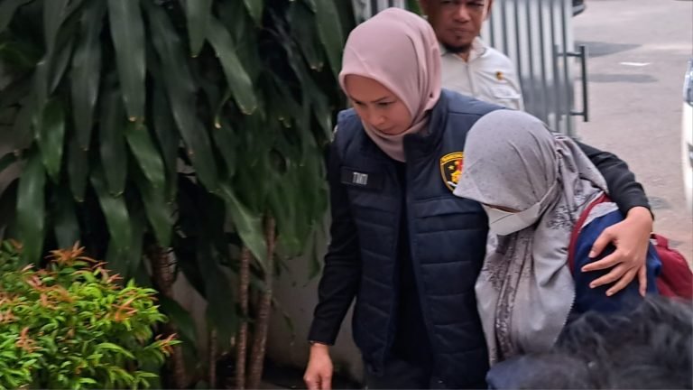 Tersangka Sri Maryani menunduk saat dirangkul penyidik menuju ruang pelimpahan di kantor kejaksaan, Kamis (1552025).