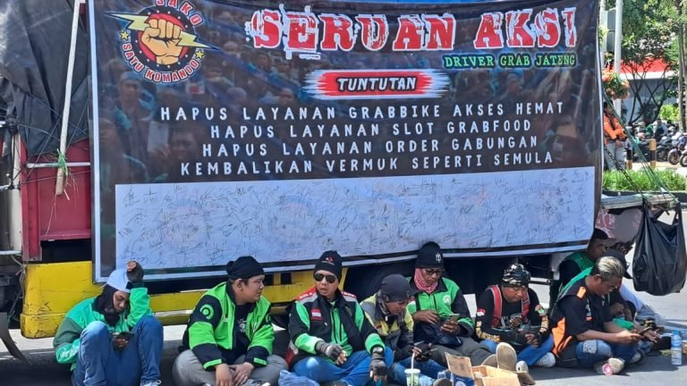 Massa aksi demo ojol di Semarang berteduh saat menunggu orator menyampaikan aspirasi.