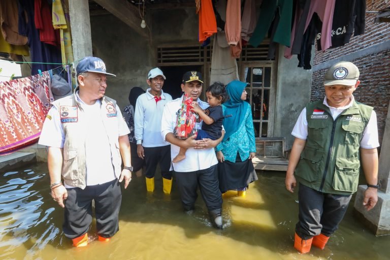 Wakil Gubernur Jateng, Taj Yasin menggendong anak saat meninjau banjir rob di Demak, Rabu (28/5/2025). (humas pemprov jateng)