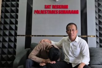 Arnendo (menunduk) didampingi kuasa hukumnya saat berada di kantor polisi menanyakan tindak lanjut laporan kasus penganiayaan. (ist)