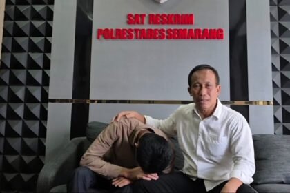 Arnendo (menunduk) didampingi kuasa hukumnya saat berada di kantor polisi menanyakan tindak lanjut laporan kasus penganiayaan. (ist)