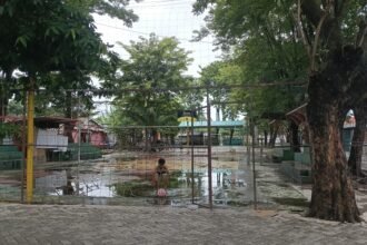 Seorang anak yang lagi mengambil bola dengan berhati-hati karena licin di genangan air yang ada di pinggir lapangan. Kamis (26/3/2026). (dul)