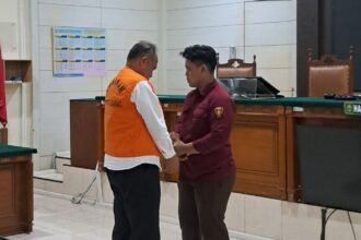 PAKAI ROMPI--Petugas kejaksaan memakaikan rompi tahanan AKPB Basuki usia sidang vonis. (bae)