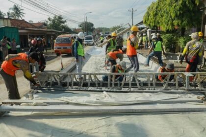 PERBAIKAN JALAN - Sejumlah pekerja melakukan pengecoran jalan rusak.