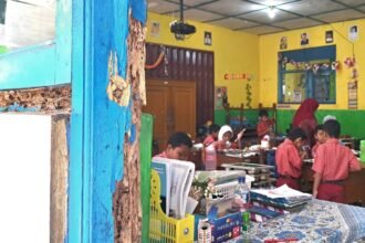 SEKOLAH RUSAK--Guru dan siswa beraktotas dalam kelas yang kusen pintu dan jendelanya keropos dimakan rayap, Selasa (28/7/2026). (bae)