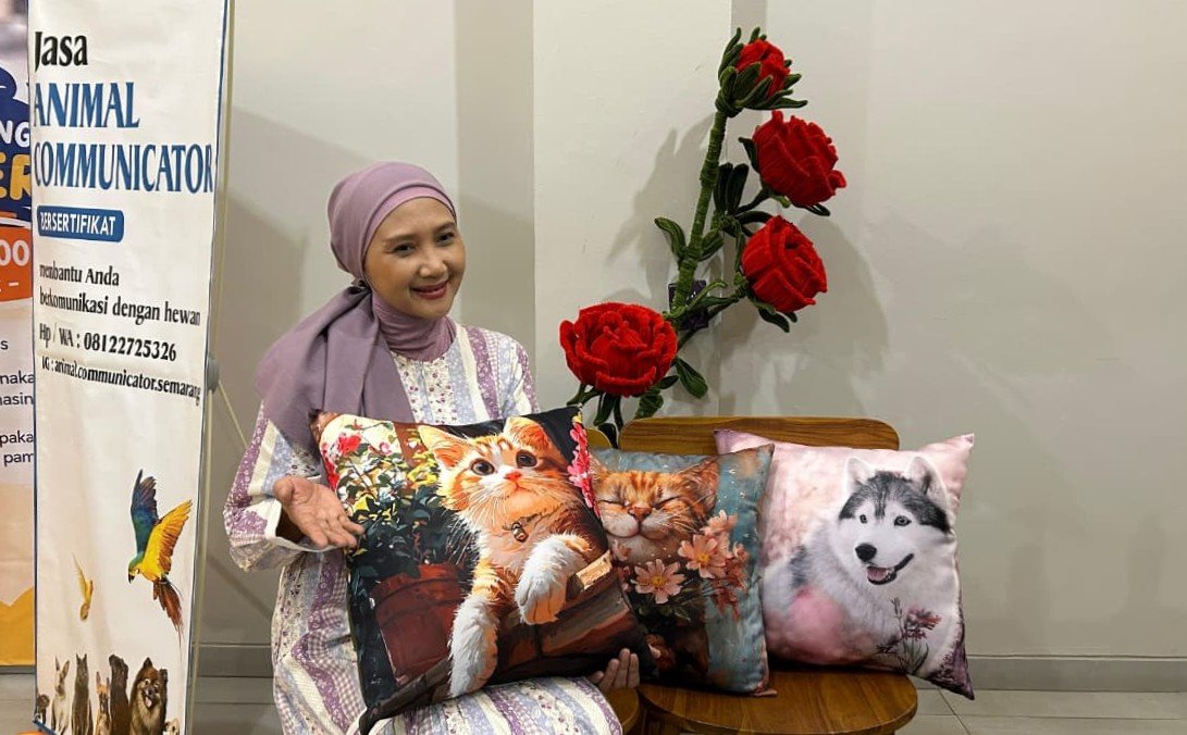BANTAL KUCING - Dina memegang bantal bergambar kucing buatan tangannya sendiri, Minggu (27/9/2026). Sebagian keuntungan dari jualan bantal kucing itu digunakan untuk memberi makan kucing jalanan. (dul)